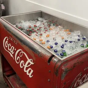 A vintage red Coca-Cola cooler full of iced bottles